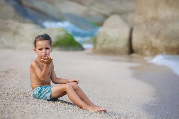Menino sentado na areia junto ao mar — Fotografia de Stock