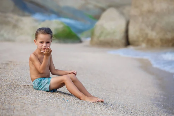 Menino sentado na areia junto ao mar — Fotografia de Stock