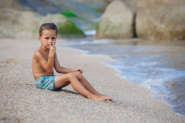 Menino sentado na areia junto ao mar — Fotografia de Stock
