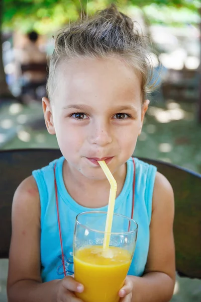 Schöner Junge trinkt Orangensaft — Stockfoto