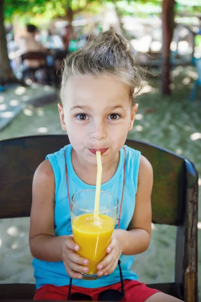 Beautiful boy is drinking orange juice — Stock Photo, Image