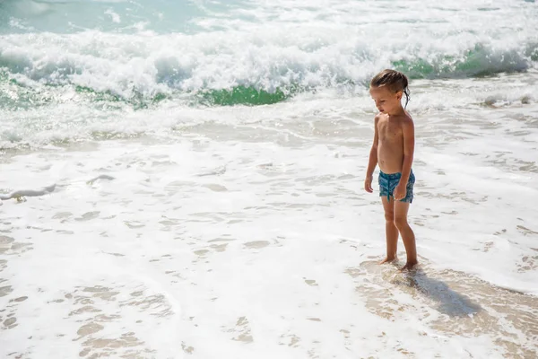 Rapaz bonito está se divertindo na praia — Fotografia de Stock