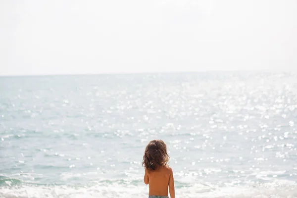Kleine vijf jaar oude jongen kijkt op de zee — Stockfoto