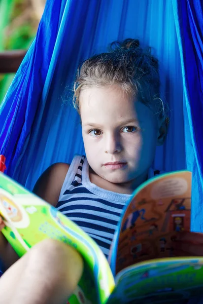 Schöner Junge liest ein Buch in einer Hängematte — Stockfoto