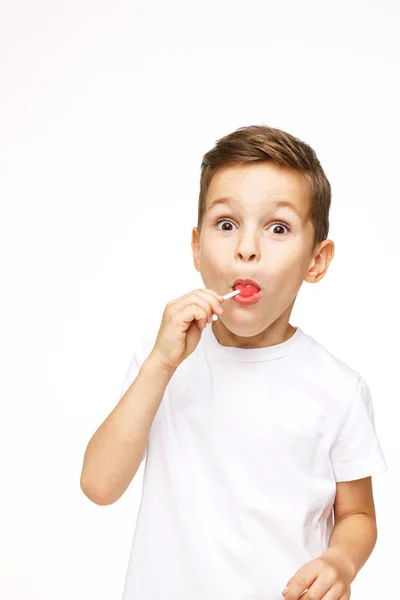 Menino com um pirulito em um fundo branco — Fotografia de Stock