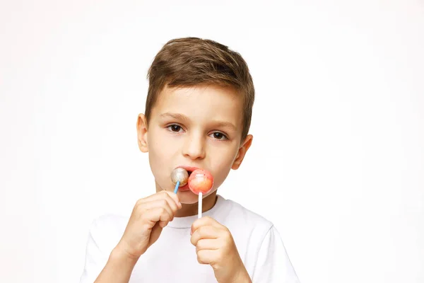 Niño pequeño con una piruleta sobre un fondo blanco — Foto de Stock