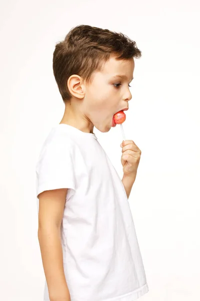 Niño pequeño con una piruleta sobre un fondo blanco —  Fotos de Stock