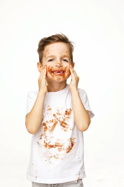 Маленький мальчик с лицом и руками в шоколаде — стоковое фото