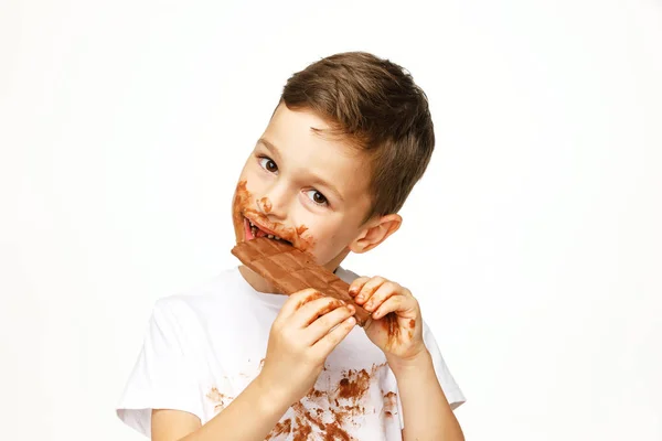 Petit garçon désordonné mange chocolat studio shot — Photo