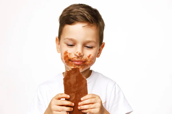 Pequeno messy menino está comendo chocolate estúdio tiro — Fotografia de Stock