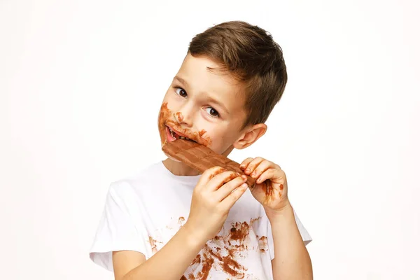 Маленький грязный мальчик ест шоколадную студию. — стоковое фото