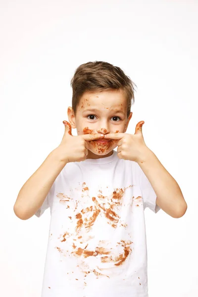 Mały chłopiec z twarzą i rękami w czekoladzie — Zdjęcie stockowe