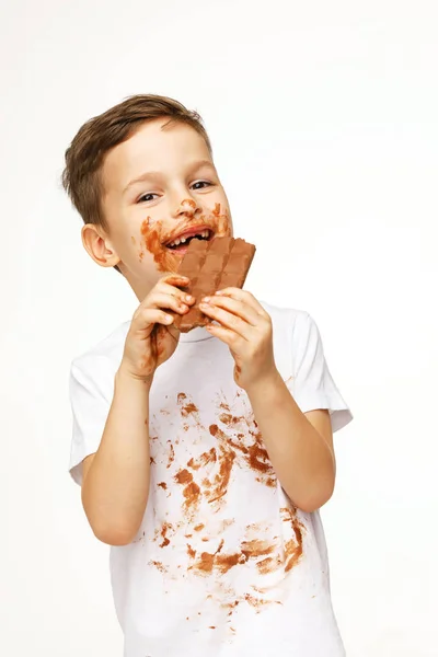 Pequeno messy menino está comendo chocolate estúdio tiro — Fotografia de Stock