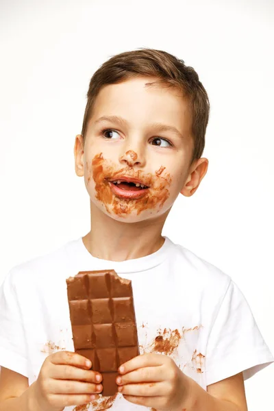 Little messy boy is eating chocolate studio shot — Stock Photo, Image