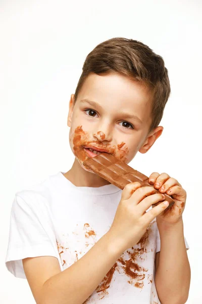 Маленький грязный мальчик ест шоколадную студию. — стоковое фото