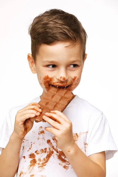 Little messy boy is eating chocolate studio shot — Stock Photo, Image