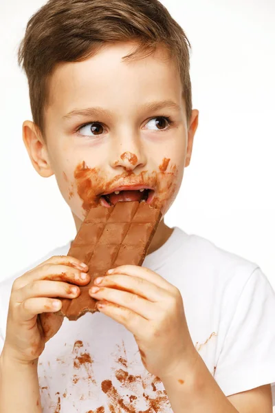 Little messy boy is eating chocolate studio shot — Stock Photo, Image