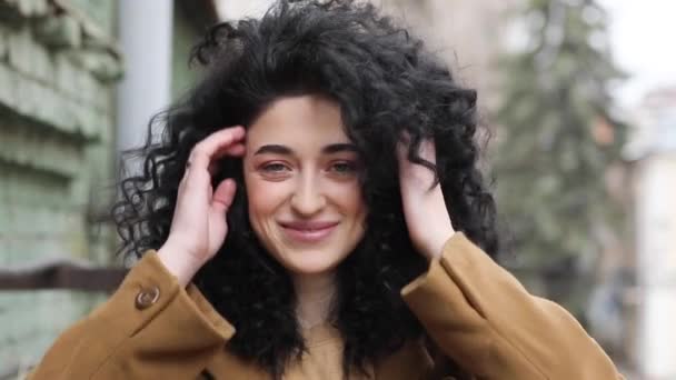 Beautiful brunette with afro hairstyle. Smiles, laughs, and cracks his head. — Stock Video