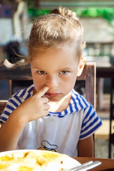 Мальчик ковыряется в носу во время завтрака — стоковое фото