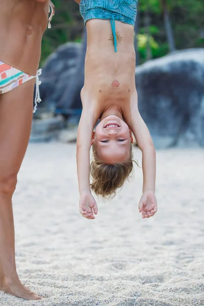 Niño de 5 años colgando boca abajo en la playa — Foto de Stock