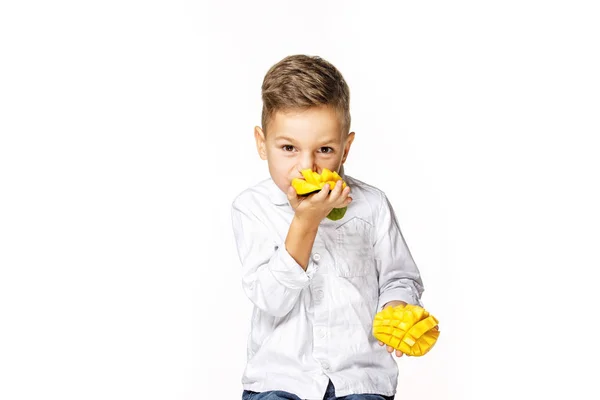 白いシャツを着たハンサムな少年がマンゴーを食べている — ストック写真