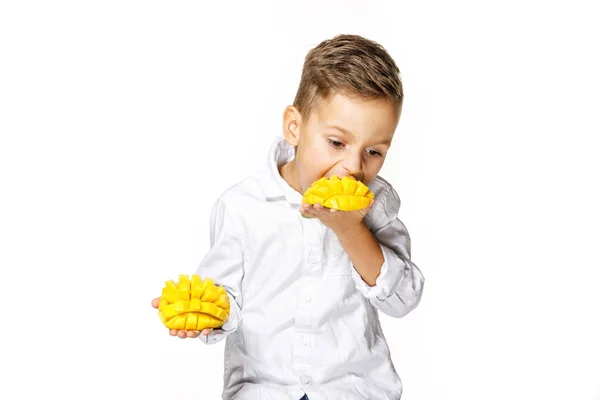 白いシャツを着たハンサムな少年がマンゴーを食べている — ストック写真