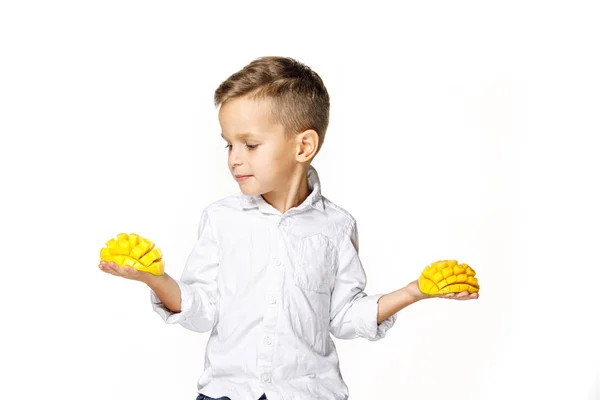 Snygg pojke i en vit skjorta med en mango — Stockfoto
