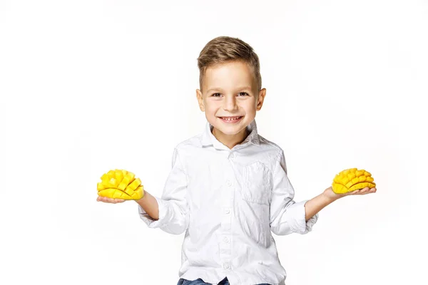 Snygg pojke i en vit skjorta med en mango — Stockfoto