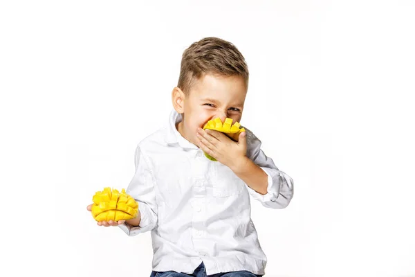 Bello ragazzo in un bianco camicia è mangiare un mango — Foto Stock