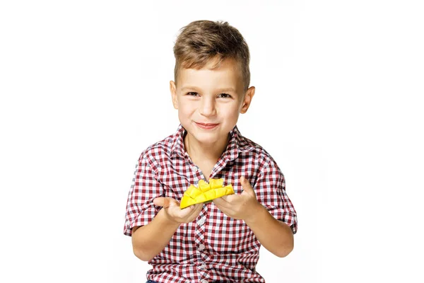 Красивый мальчик в красной рубашке ест манго — стоковое фото