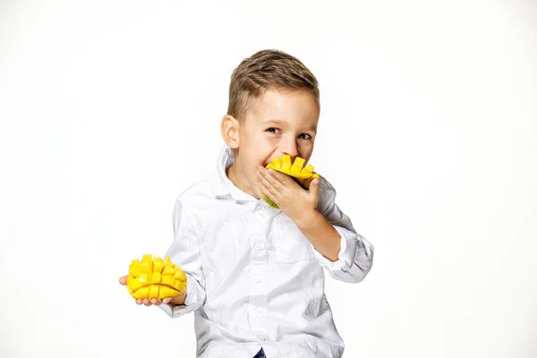 Fešák v bílé košili žere mango — Stock fotografie