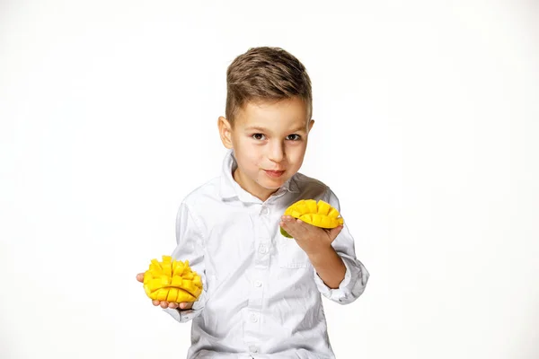 Snygg pojke i en vit skjorta med en mango — Stockfoto