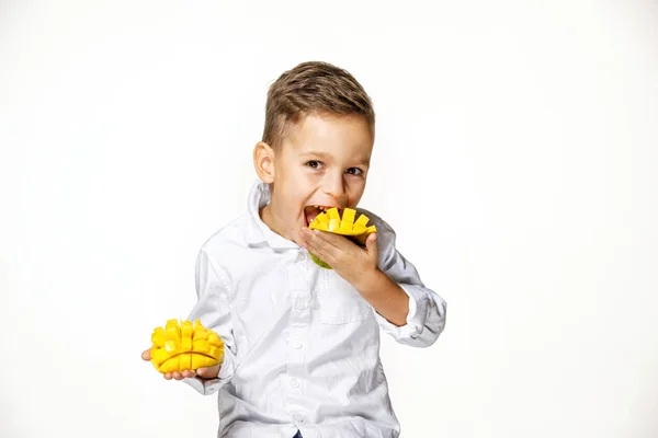 Fešák v bílé košili žere mango — Stock fotografie