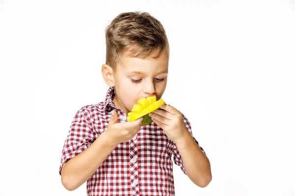 Bello ragazzo in un rosso camicia è mangiare un mango — Foto Stock
