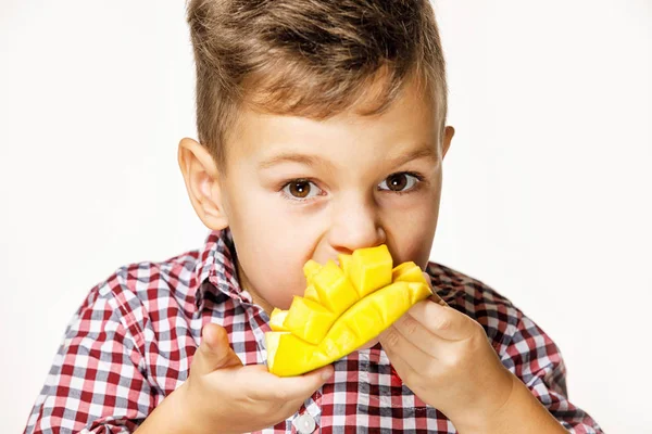 Bello ragazzo in un rosso camicia è mangiare un mango — Foto Stock