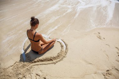 Plajda Lotus pozisyonunda güzel bir kız.