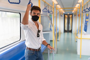 Coronavirus salgını sırasında metroda yüz maskesi takan yeni, normal, çekici beyaz bir adam iş gezisi sırasında yüz koruyucusu ve günlük beyaz gömlek giyen bir adam..