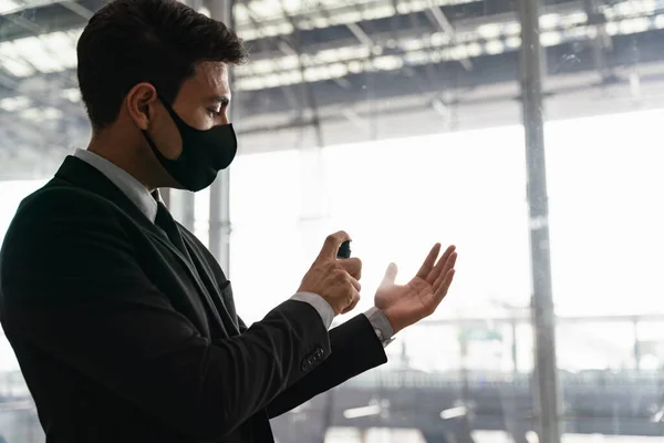 Business man wearing face mask or face shield using liquid hand sanitizer, alcohol spray to clean his hand during Coronavirus pandemic, new normal lifestyle, healthcare and hygiene protection.