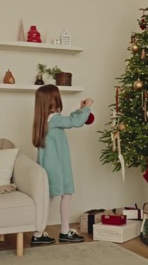 Noel ağacını Noel arifesinde Noel oyuncaklarıyla süsleyen güzel bir kız. Noel evinin içi, sihirli ruh hali. - Mutlu yıllar. Sinematik ağır çekim.