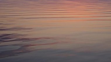 Sakin okyanus dalgaları yavaş çekim günbatımında, pürüzsüz pembe mavi su arka planı rahatlama ve tasarım için.
