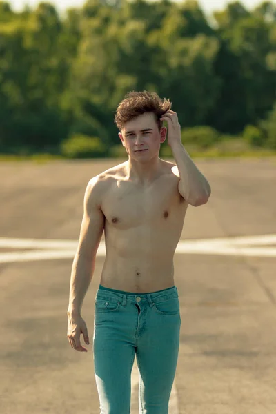 前方を歩く若い成人男性彼の髪を暖かい夏の日に手を実行しているときに上半身裸 — ストック写真