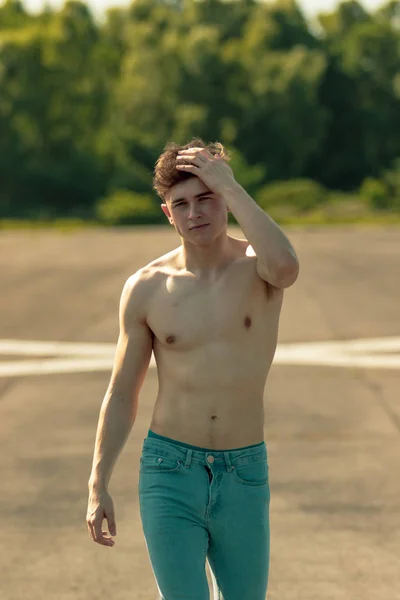 前方を歩く若い成人男性彼の髪を暖かい夏の日に手を実行しているときに上半身裸 — ストック写真