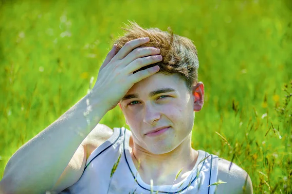 Sıcak bir yaz gününde amoung uzun çim döşeme genç bir yetişkin erkek