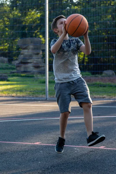 Pre-teen boy playing with a basketball in a park