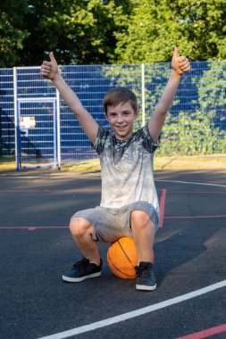 Bir sepet topu üzerinde oturan mutlu pre-Teen Çocuk. Bir oyun kavramını kazanma
