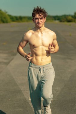 Genç bir beyaz yetişkin erkek sıcak bir yaz gününde gömleksiz koşu