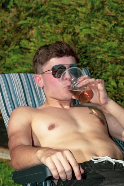 Young male adult laying in the sun with a beer