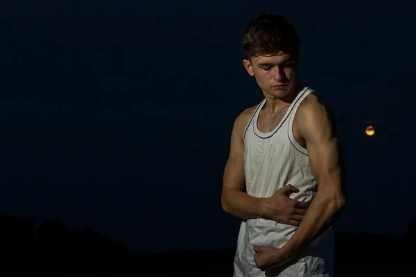 外面的年轻男性成人用月亮弯曲双臂 — 图库照片