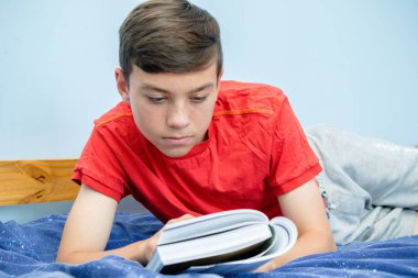 Beyaz genç çocuk yatağı üzerinde döşeme bir kitap okuma