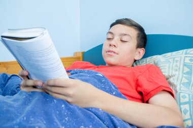 Beyaz genç çocuk yatağı üzerinde döşeme bir kitap okuma